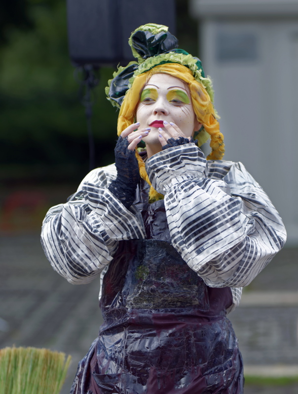 19 - A person wearing a theatrical costume featuring a striped blouse and a dark, glossy apron